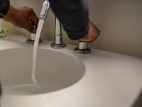 Lavatorio blanco con el caño abierto y agua corriendo