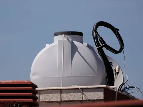 Tanque de agua blanco instalado en una azotea con cielo azul